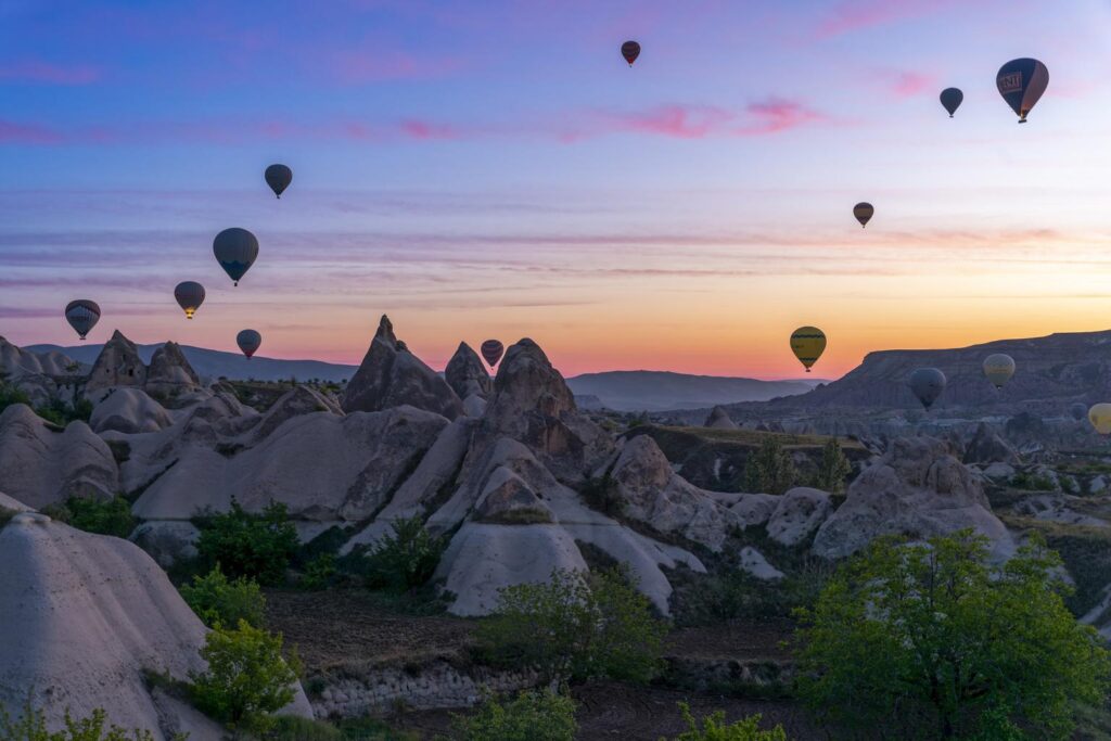 Hot air balloons flying over Cappadocia at sunrise in Turkey